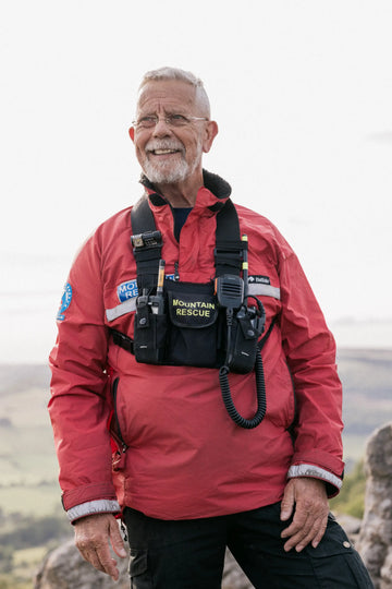 Man in a red mountain rescue jacket with equipment on a mountainous background