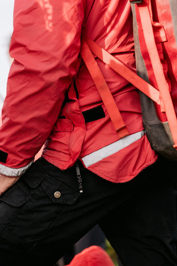 Person wearing a buffalo systems red jacket with orange straps over a black garment.