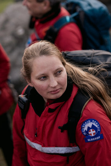 Person wearing a red buffalo systems mountain rescue jacket with a visible logo.