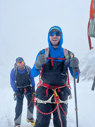Two climbers in buffalo systems winter gear on a snowy mountain, on a rescue mission