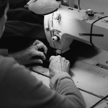 Person operating a sewing machine with close-up of hands and machine.
