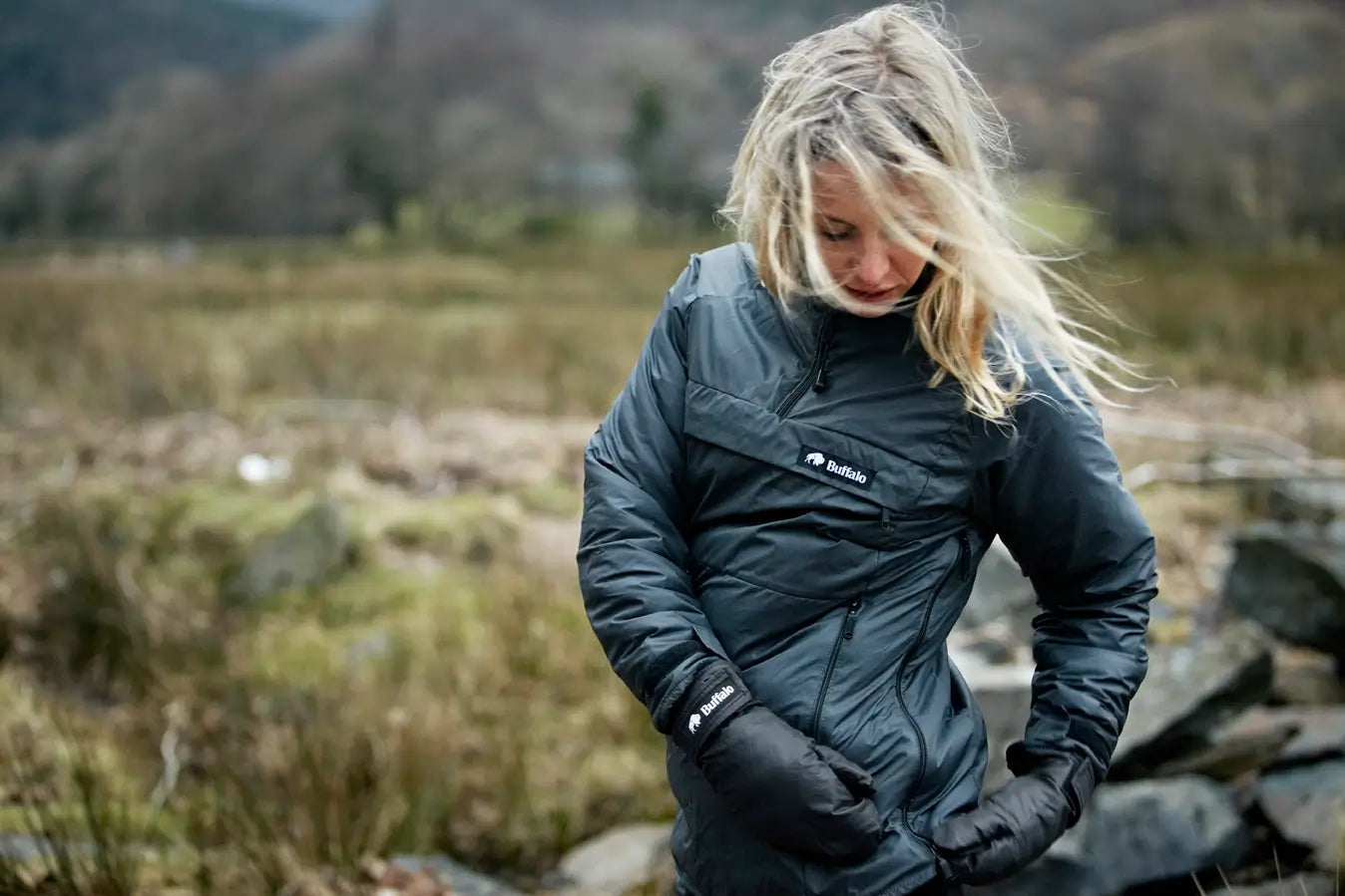 Woman wearing a gray jacket with a buffalo systems logo on a mountain hike