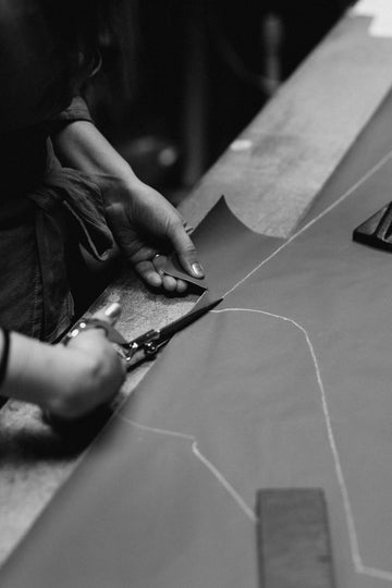 Person cutting fabric with scissors on a table