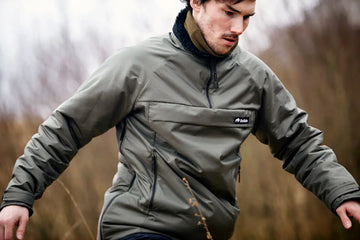 Man wearing a green jacket outdoors with a blurred natural background