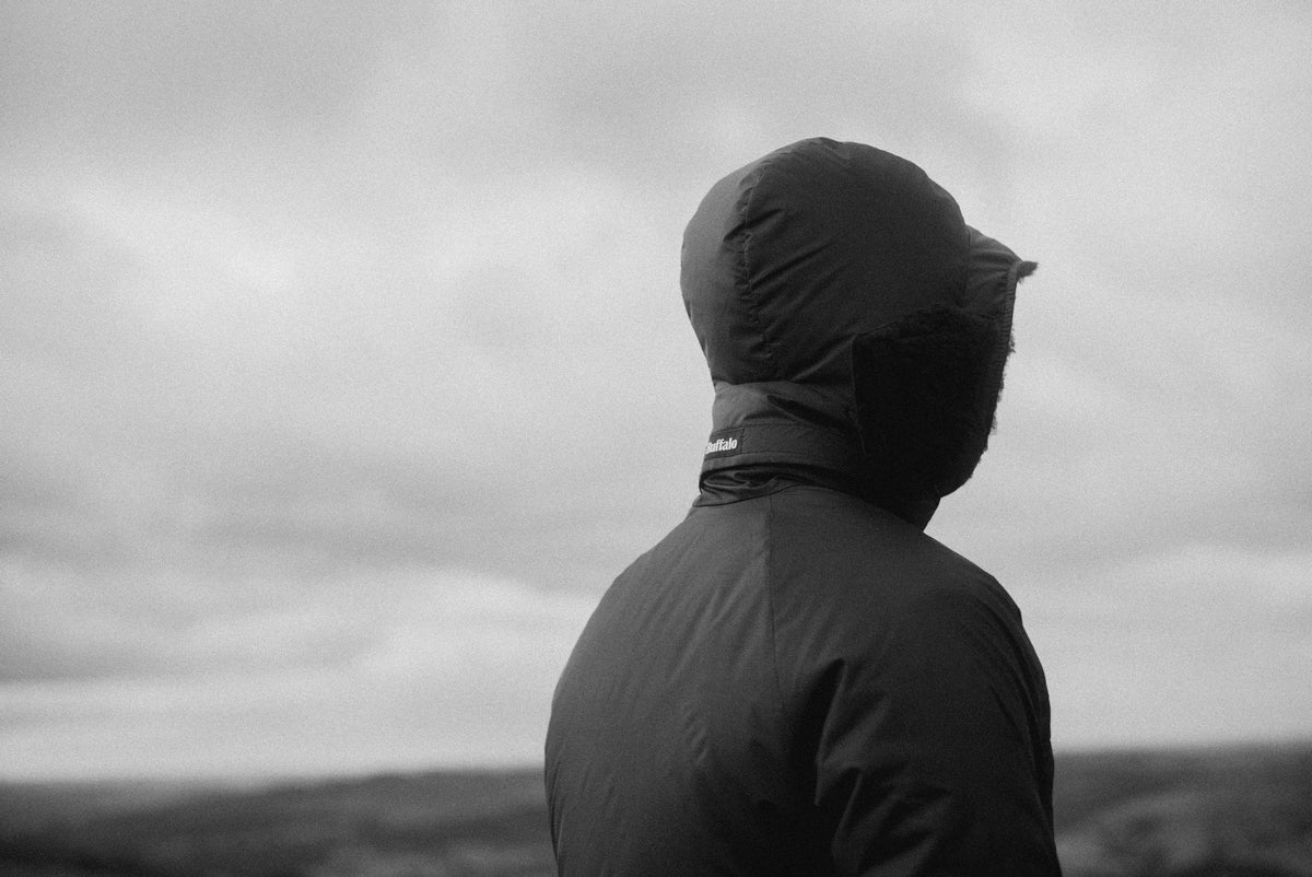 Person wearing a hooded jacket looking at a cloudy sky