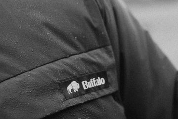 Close-up of a 'Buffalo' brand label on a dark fabric surface.