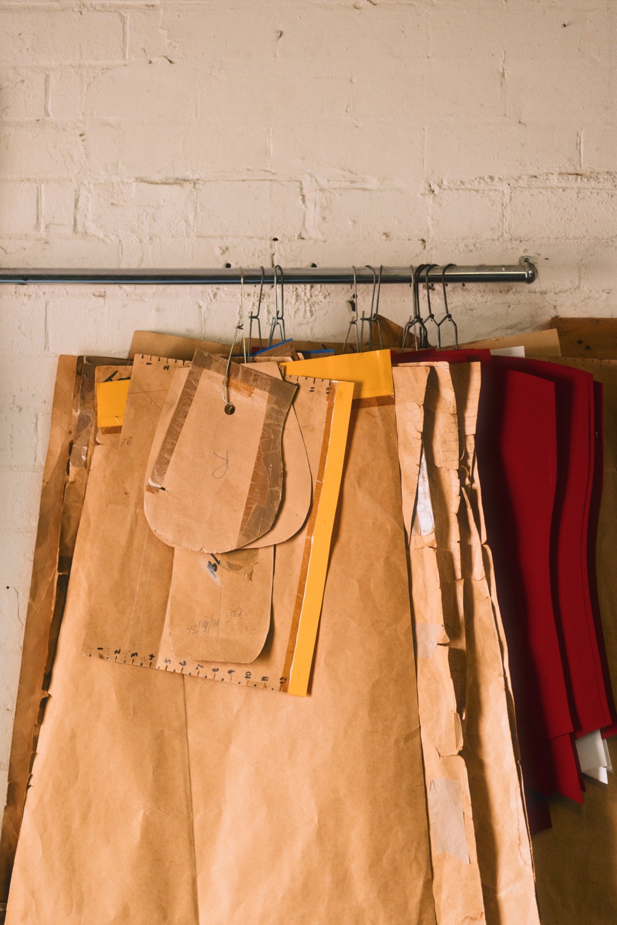 Set of patterns hanging on a rack against a brick wall.