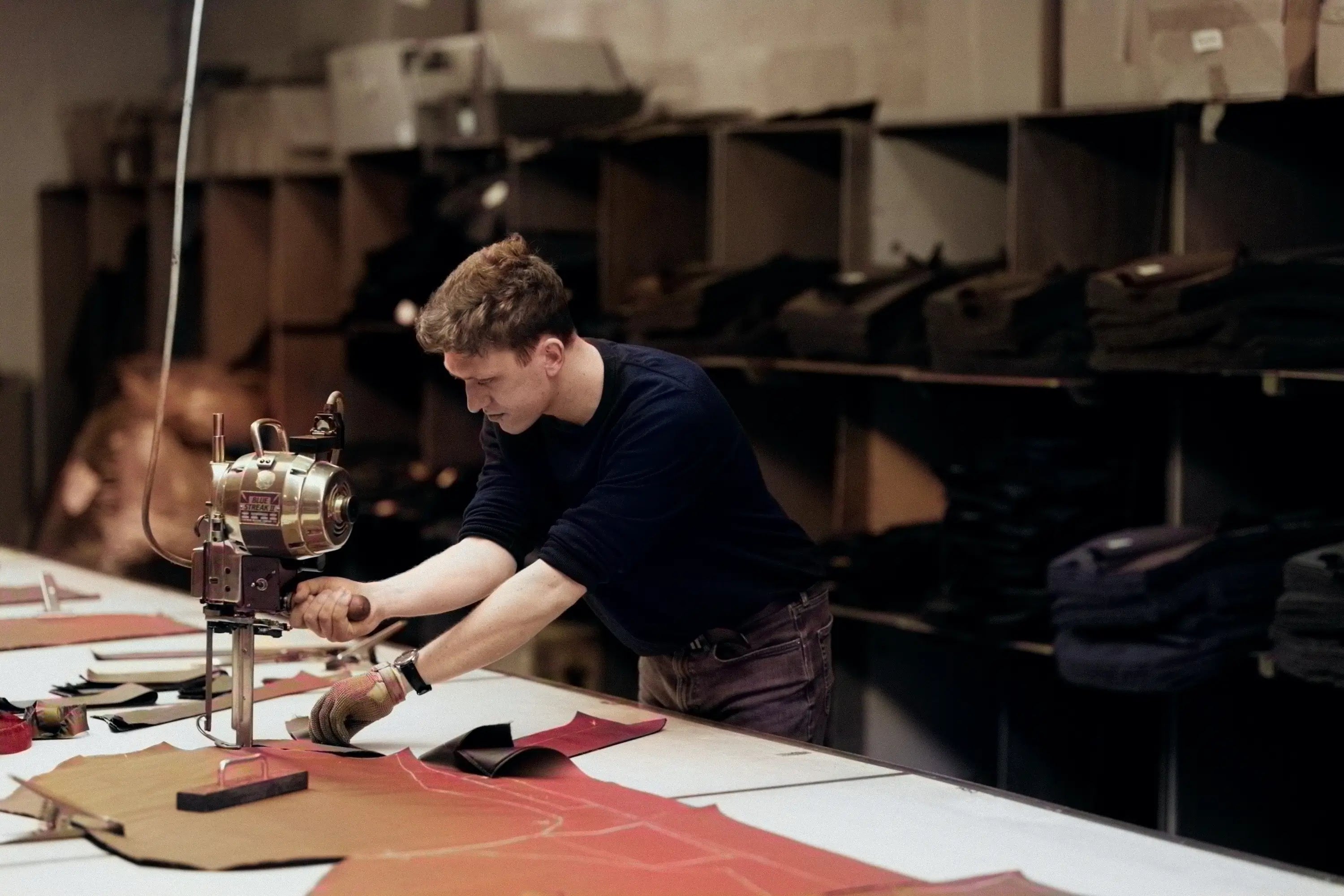 Person working wit cutting fabric at a table in a workshop setting