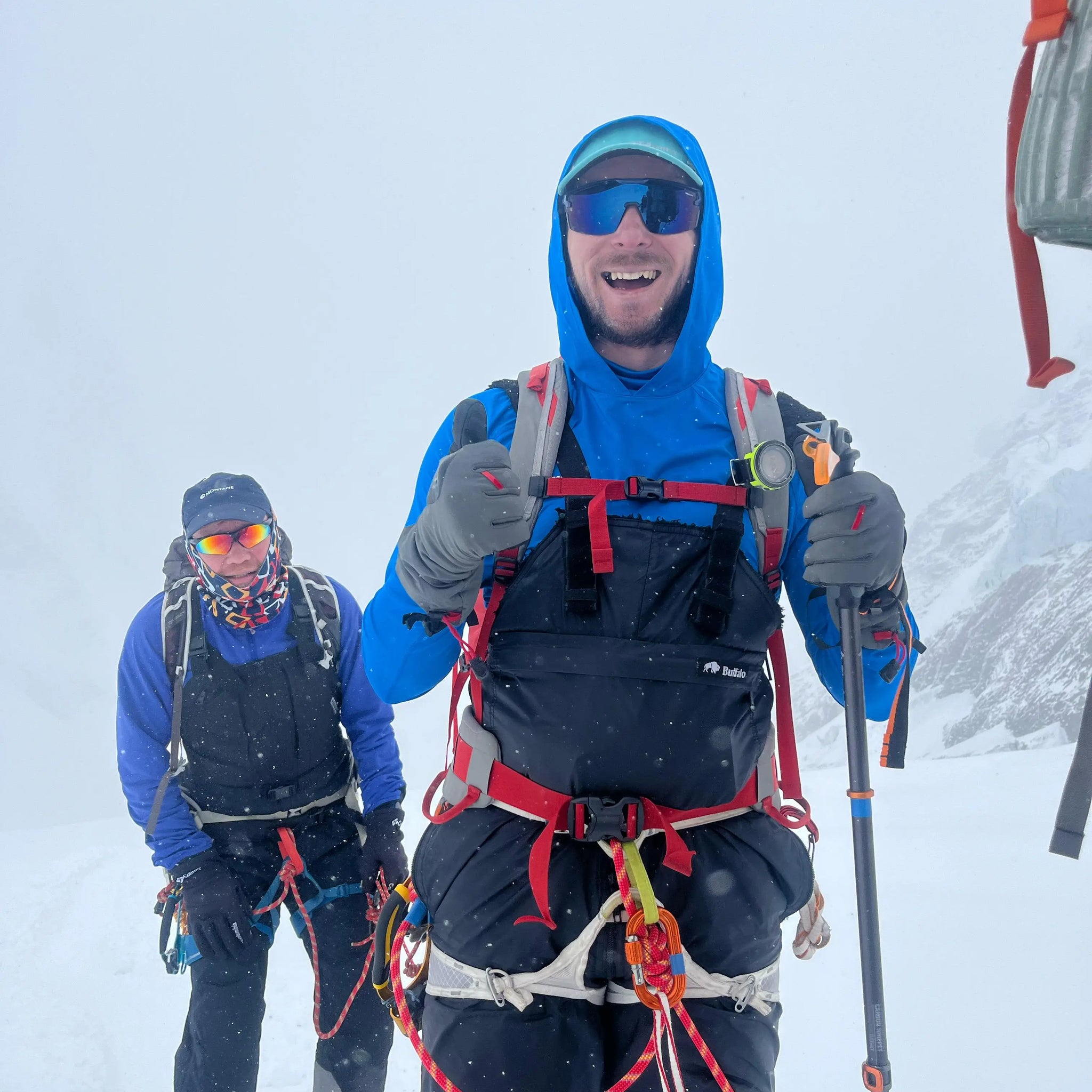 Two climbers in buffalo systems winter gear on a snowy mountain, on a rescue mission